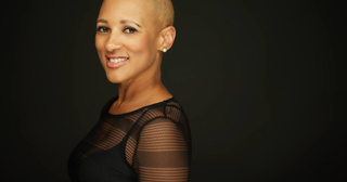 Chris-Tia Donaldson smiling in a black mesh top on a dark background
