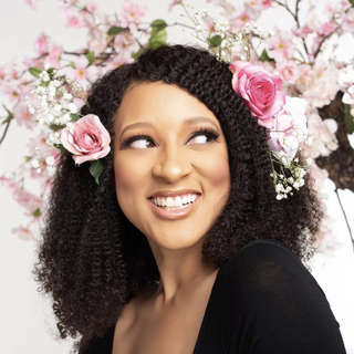Chris-Tia Donaldson, tgin founder, smiling with pink roses in her curly hair
