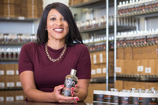 Chris-Tia Donaldson holding a tgin bottle in a stockroom