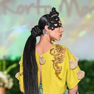 Runway model with a long sleek braided ponytail and sculpted braids in a yellow top