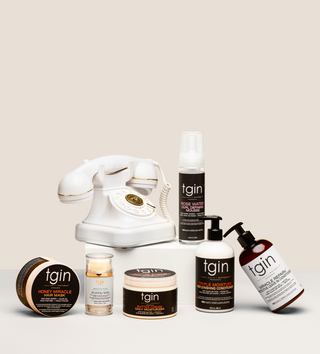 tgin bestsellers including Honey Miracle Hair Mask, Butter Cream Daily Moisturizer, Rose Water Curl Defining Mousse and Triple Moisture Replenishing Conditioner beside a white vintage telephone