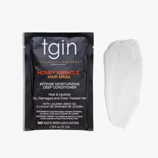 A single TGIN Honey Miracle Hair Mask sachet next to a dollop of the white hair mask cream on a clean white background.