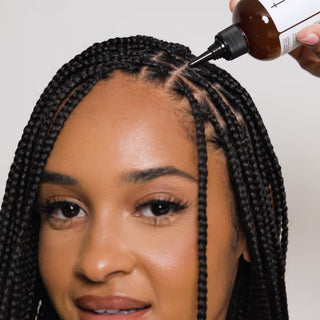 Woman with box braids having serum applied to her scalp parts from a brown nozzle bottle
