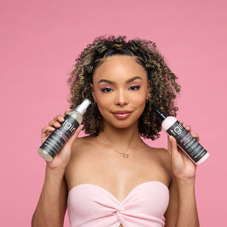 Woman with curly hair holding two tgin Rose Water products on a pink background
