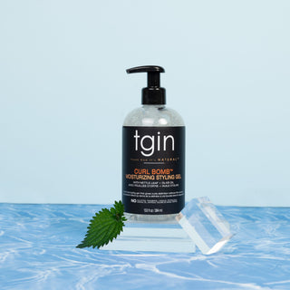 tgin Curl Bomb Moisturizing Styling Gel on a clear block with a nettle leaf on a blue background