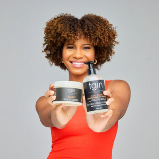 Smiling woman with curly hair holding out tgin Curl Bomb Moisturizing Styling Gel and a tgin jar