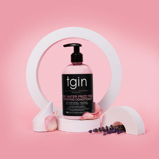 tgin Rose Water Frizz Free Hydrating Conditioner on a white stand with rose petals and lavender