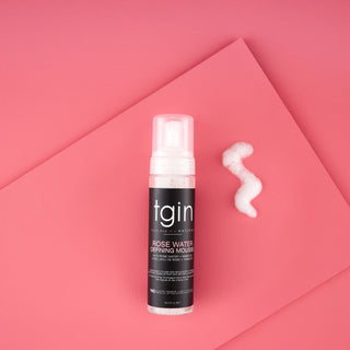 tgin Rose Water Curl Defining Mousse bottle with a swirl of foam on a pink background