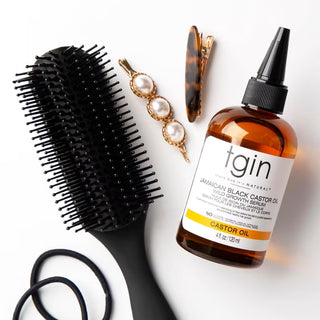 tgin Jamaican Black Castor Oil Wild Growth Serum with a hair brush, hair clips and hair ties