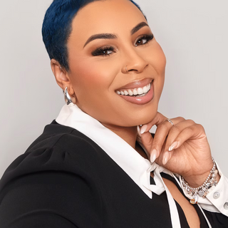 Aris Singleton, tgin CEO, smiling with short blue hair in a black top with a white collar