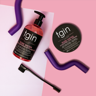 tgin Rose Water Curl Defining Styling Gel and Hydrating Curl Cream with an edge brush and purple flexi rods on a pink background