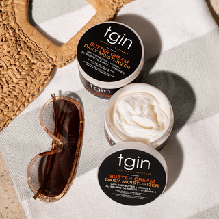Two jars of tgin Butter Cream Daily Moisturizer, one open, on a striped towel with sunglasses and a woven bag