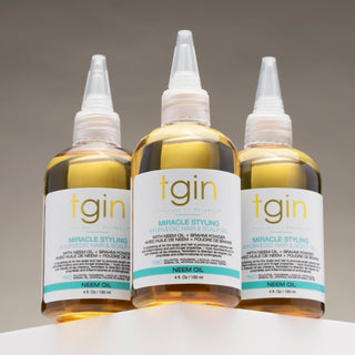 Three bottles of tgin Miracle Styling Ayurvedic Hair & Scalp Oil with neem oil on a white ledge