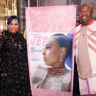 Two guests posing beside a large JET Collector's Edition cover featuring Aris Singleton, CEO of tgin