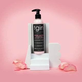 tgin Rose Water Hydrating Styling Lotion bottle on white blocks with rose petals on a pink background