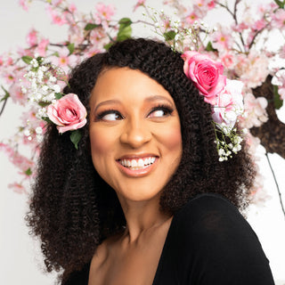 Chris-Tia Donaldson, tgin founder, smiling with pink roses in her curly hair