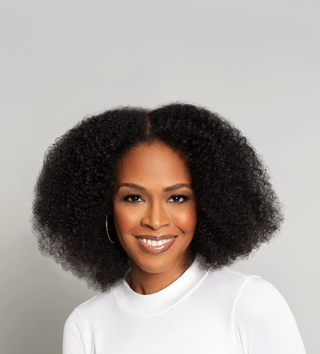 Smiling woman with full coily natural hair in a white top