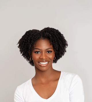 Smiling woman with short coily natural hair in a white top