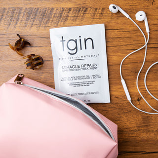 tgin Miracle RepaiRx CPR Protein Treatment packet on wood with hair clips, earbuds, and a pink pouch
